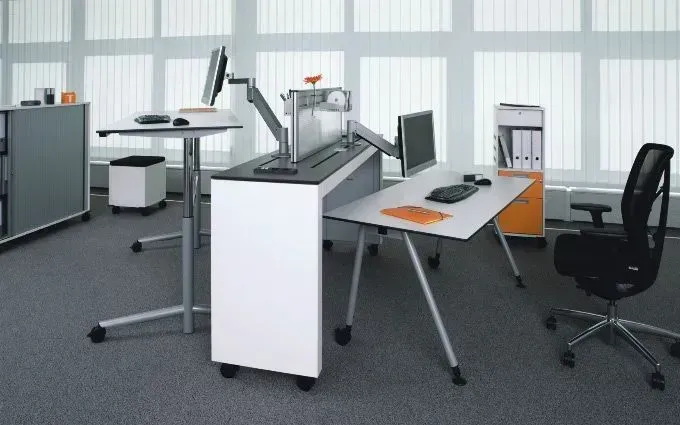 Ein Schreibtisch mit einem Computer darauf in einem Büro