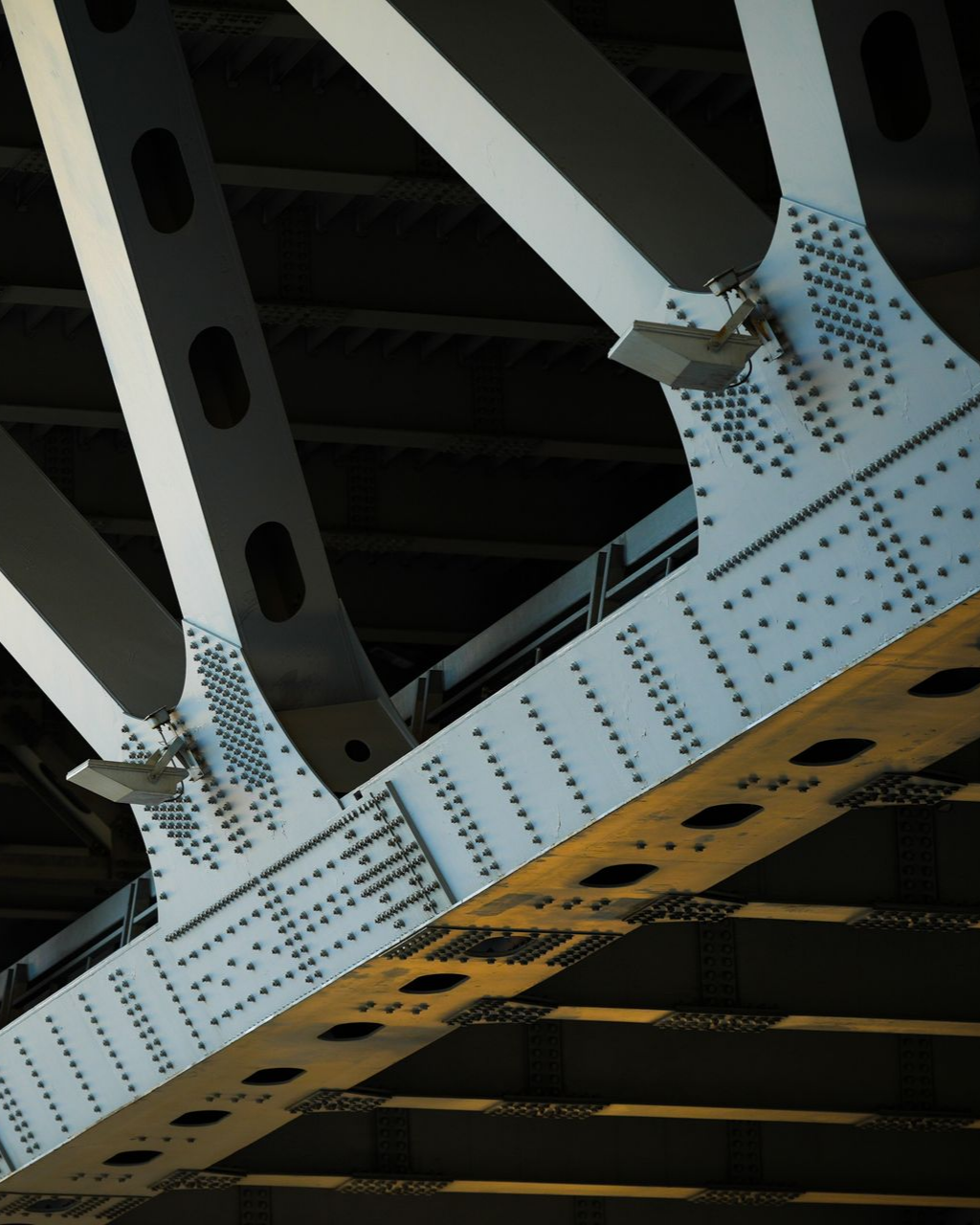 Gros plan de la structure en acier d'un pont, montrant des rivets, des poutres de support et une ferme diagonale.