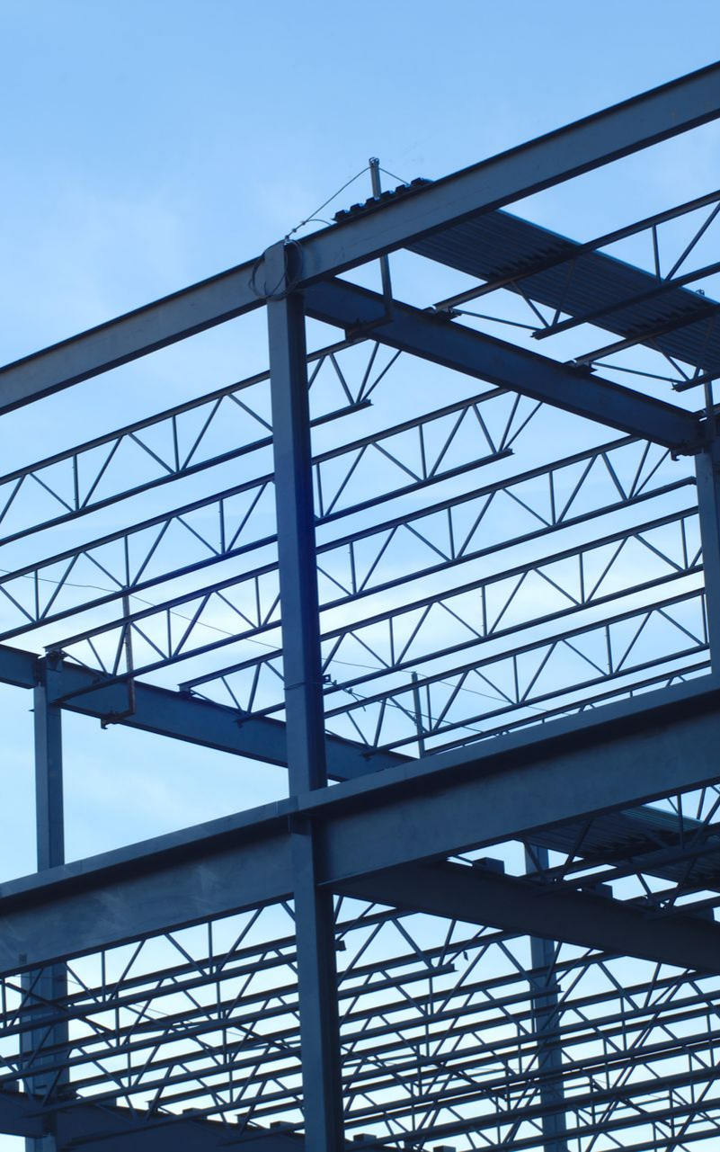 Structure en acier d'un bâtiment en construction, avec un ciel bleu en arrière-plan.