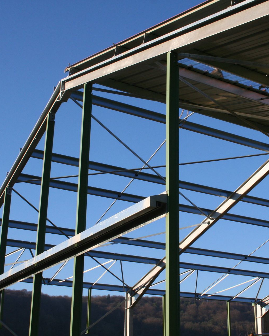 Structure en acier vert et argent d'un bâtiment sous un ciel bleu clair.