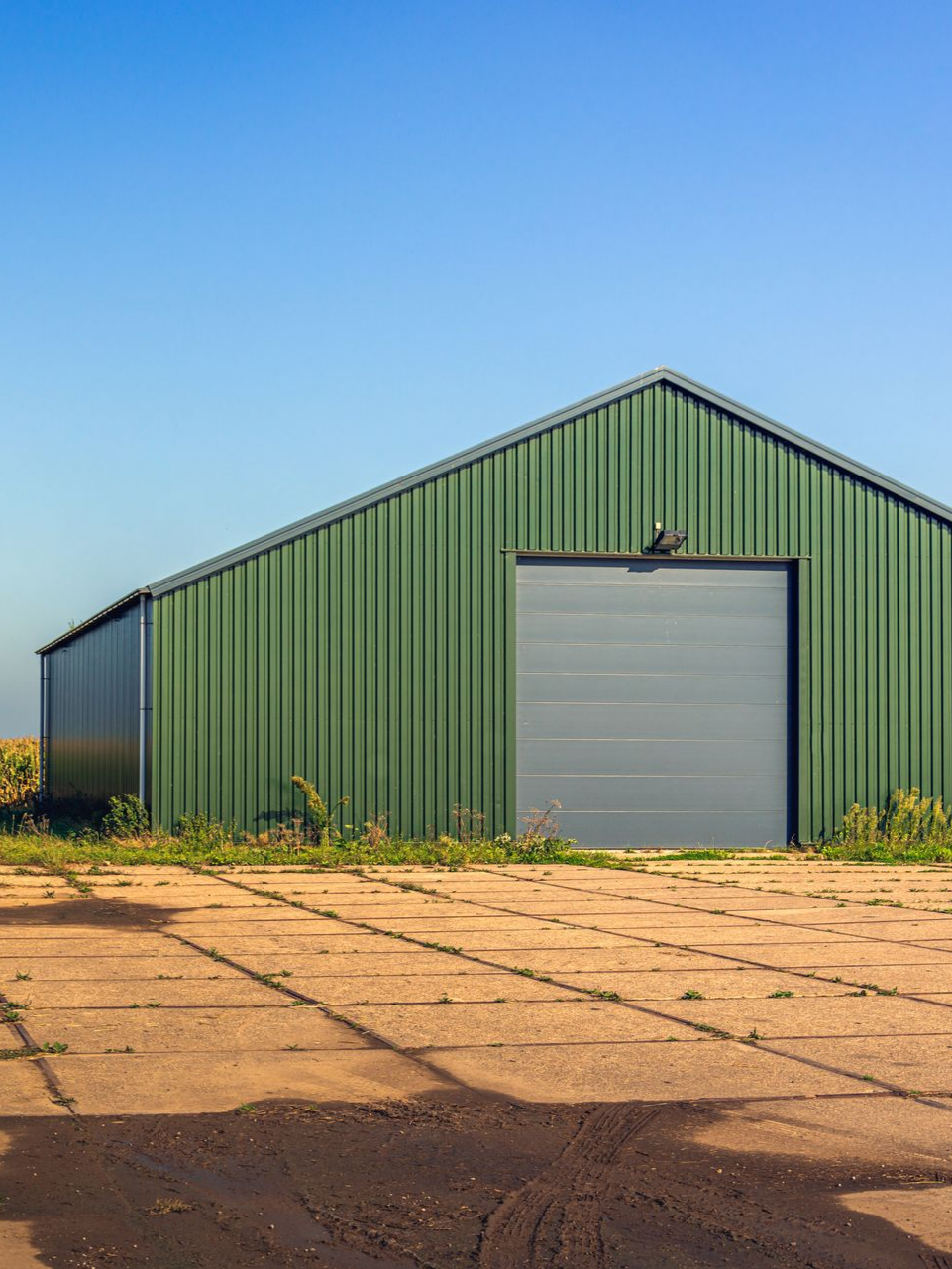 Entrepôt en métal vert avec une porte de garage