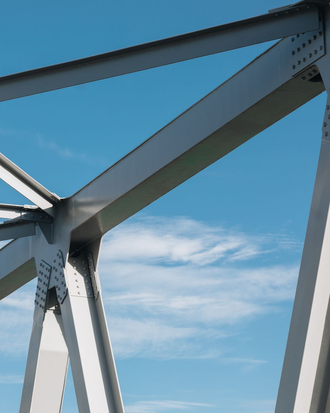 Structure de pont en acier contre un ciel bleu vif avec quelques nuages.