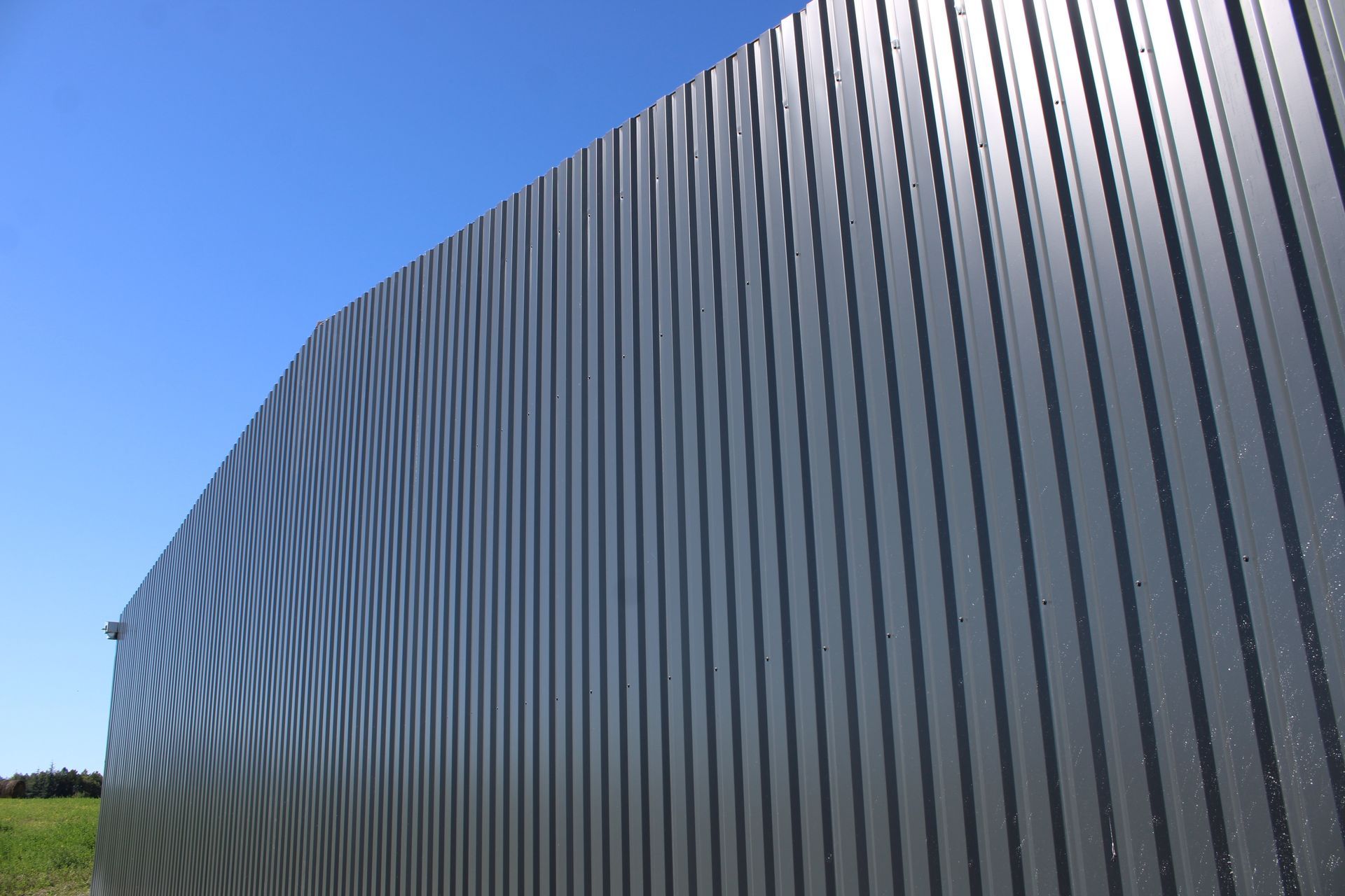 Mur en tôle ondulée grise sous un ciel bleu vif.