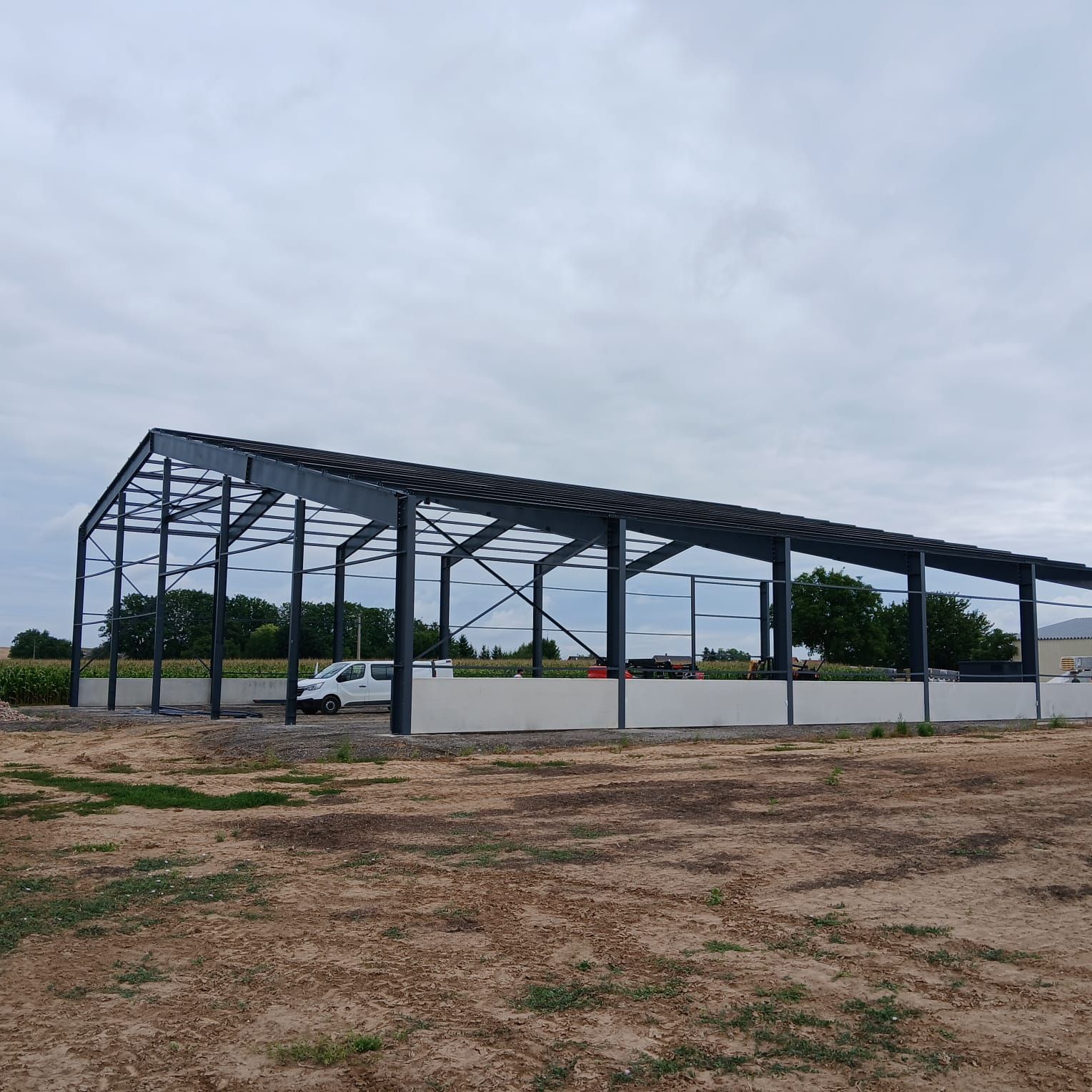 Structure en acier d'un grand bâtiment en construction contre un ciel nuageux.