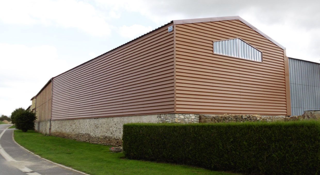 Abri d'auto en métal noir avec un toit translucide, situé à l'extérieur avec des arbres en arrière-plan.