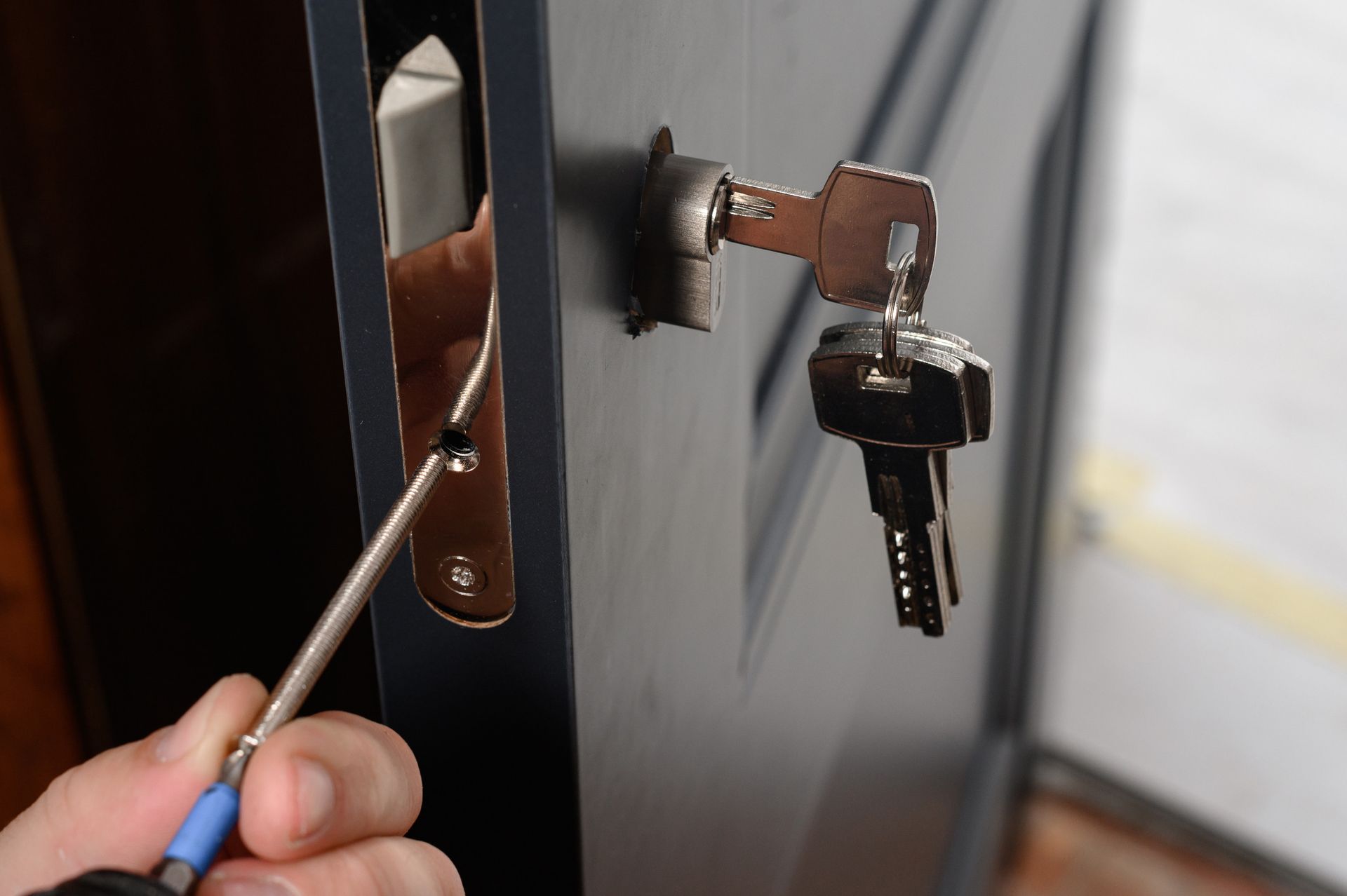 Una persona está arreglando una cerradura de puerta con un destornillador.