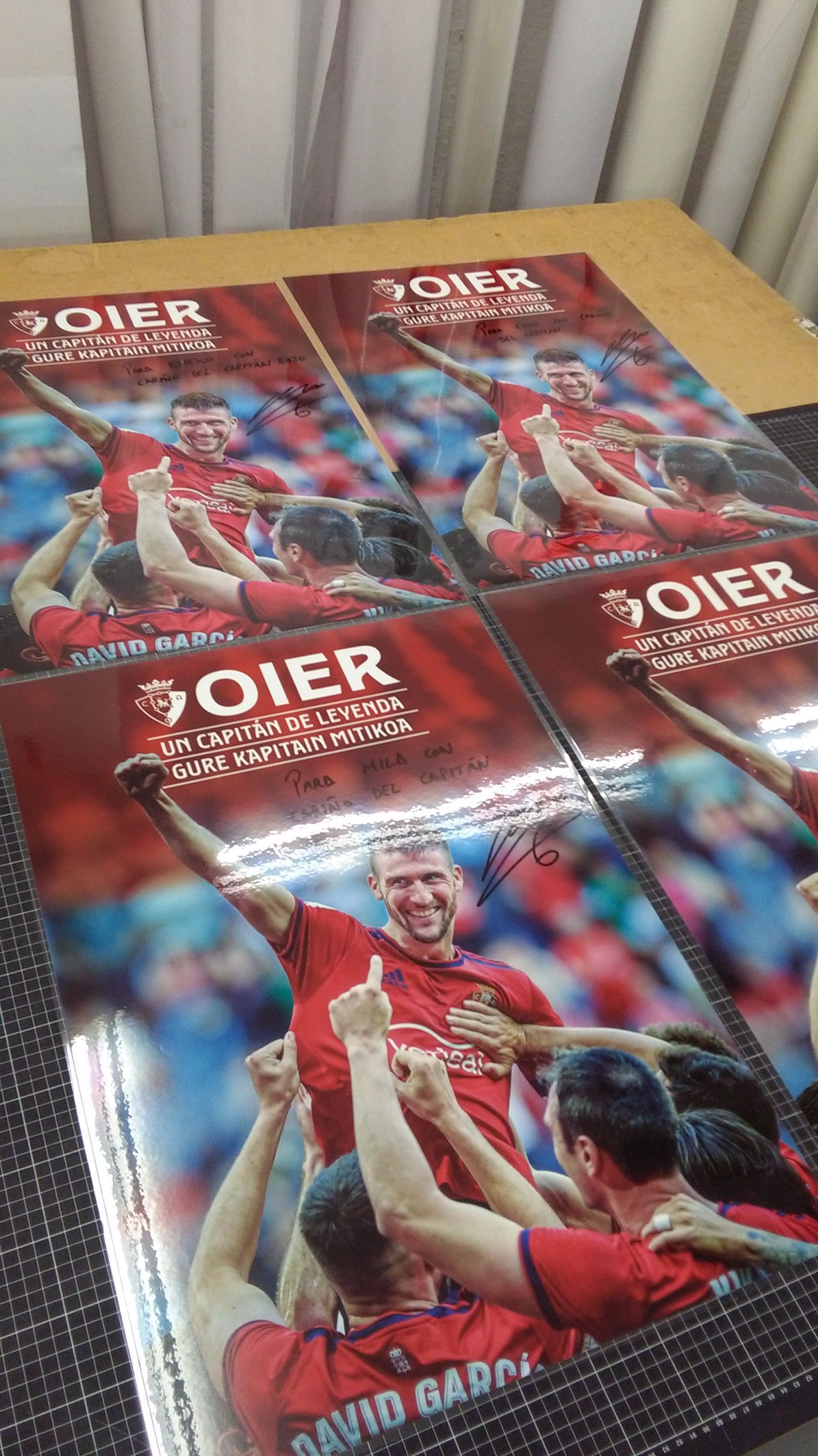 Un grupo de carteles de fútbol están colocados encima de una mesa de madera.