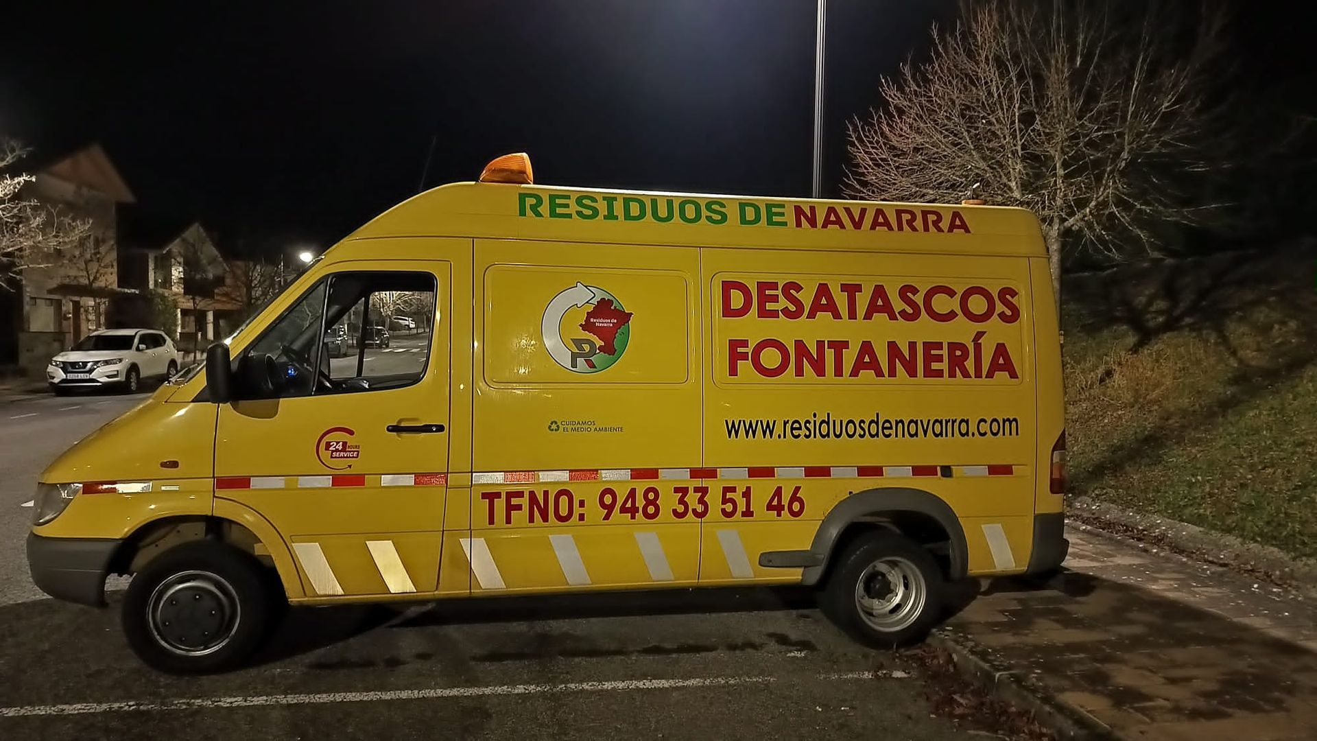 Una furgoneta amarilla de desatascos fontaneria esta estacionada al costado de la carretera