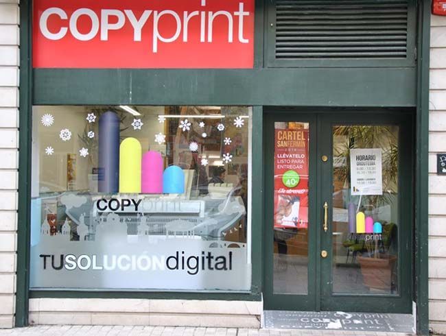 El frente de una tienda de copias impresas con un cartel rojo.