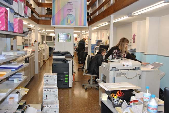 Una mujer se sienta en un escritorio en una oficina grande.