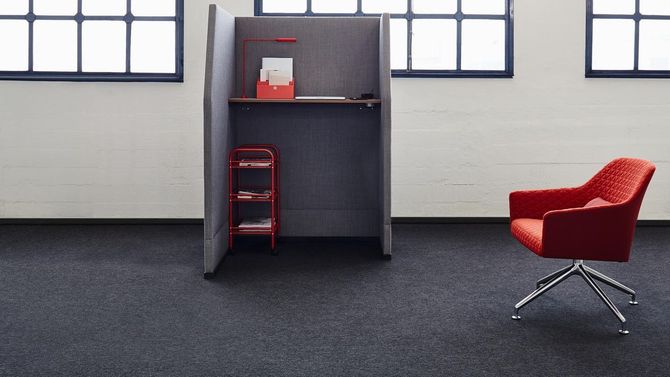 Una silla roja está sentada frente a un cubículo en una habitación.