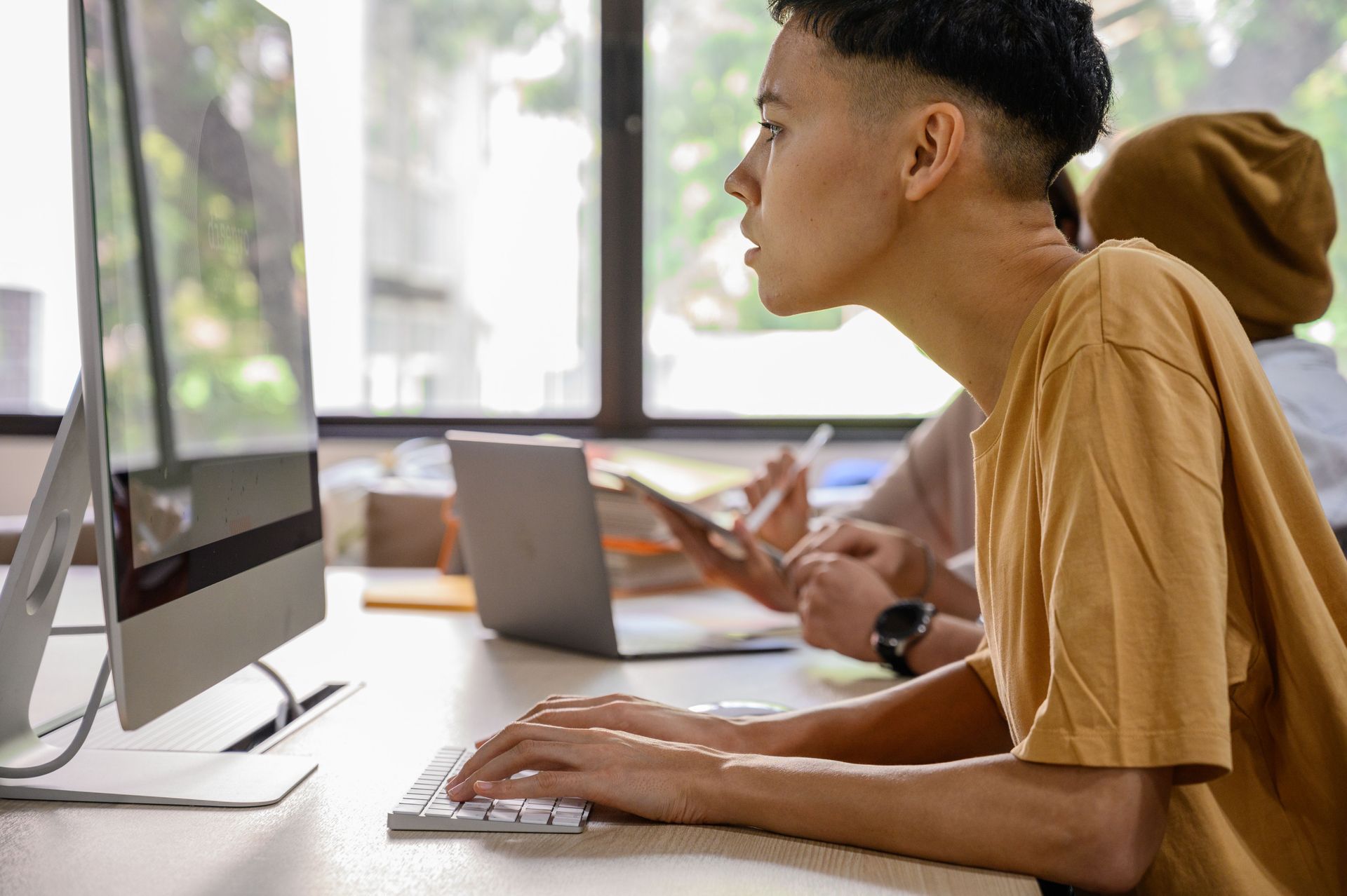 Personne en train de taper au clavier à un bureau dans un bureau lumineux, regardant un écran d’ordinateur.