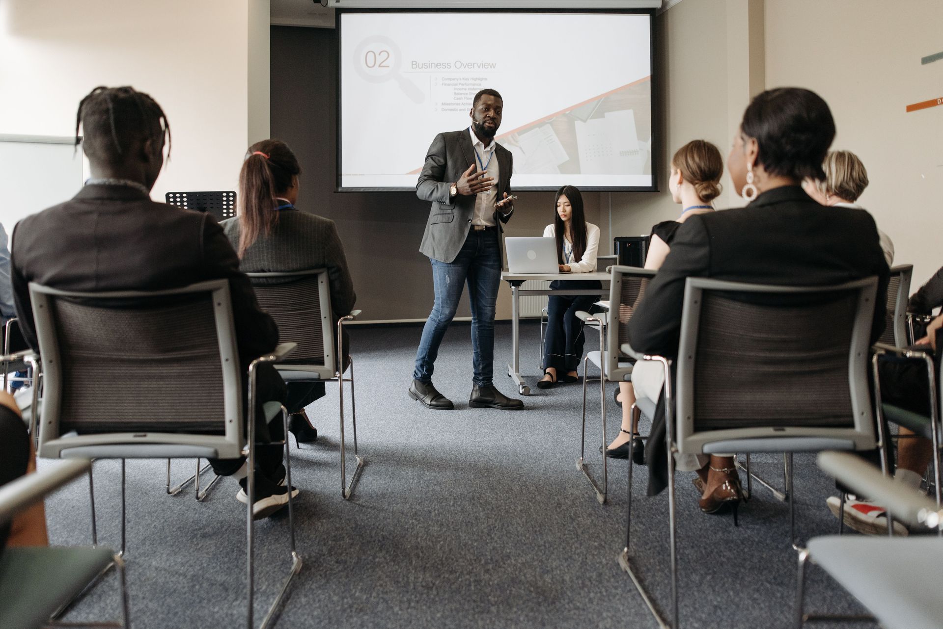 Présentation professionnelle dans une salle de conférence, avec un intervenant s’adressant aux participants assis.
