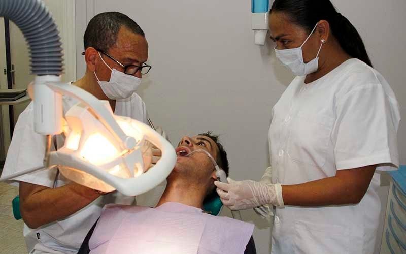 Un hombre está siendo examinado por dos dentistas en un consultorio dental.