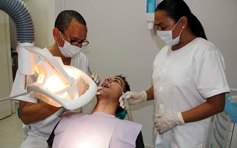 Un hombre está siendo examinado por dos dentistas en un consultorio dental.