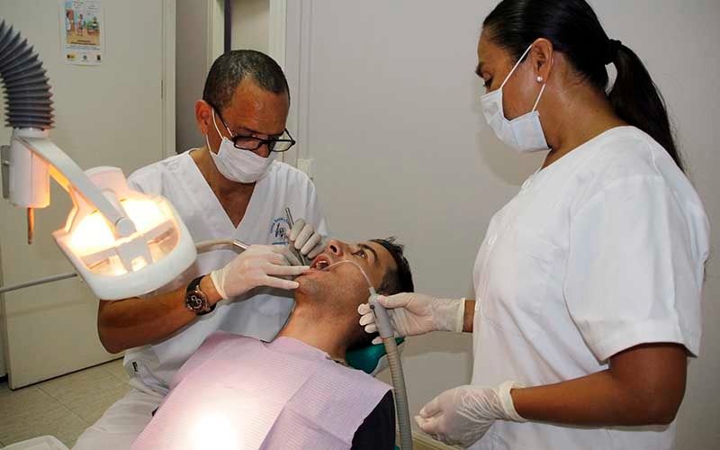 Un hombre está siendo examinado por dos dentistas.