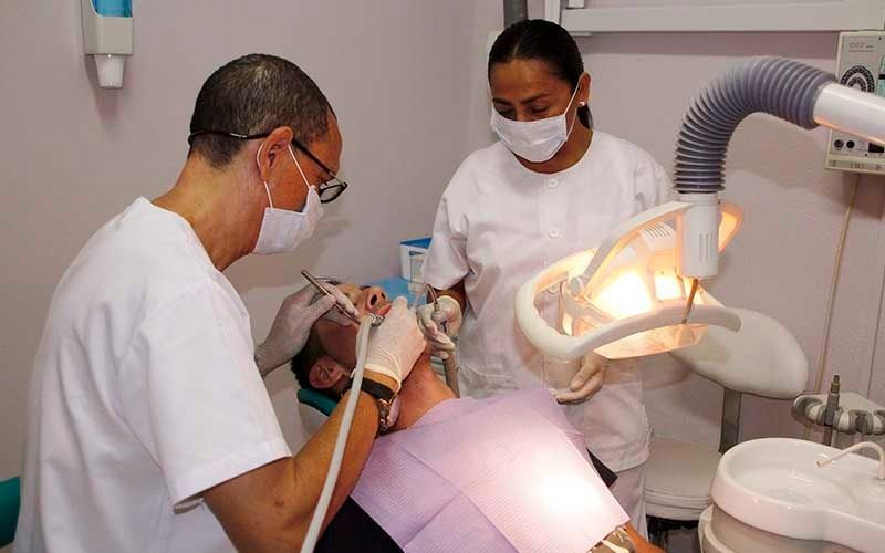 Un dentista y una enfermera están examinando los dientes de un paciente en un consultorio dental.