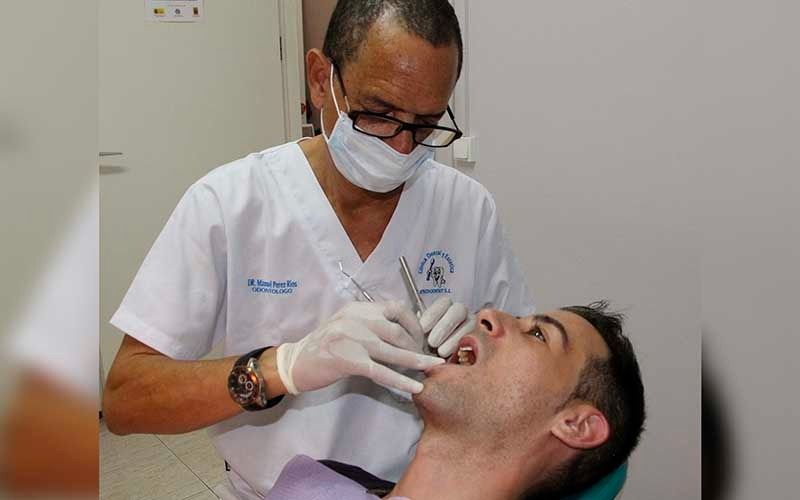 Un dentista está examinando los dientes de un hombre en una silla dental.