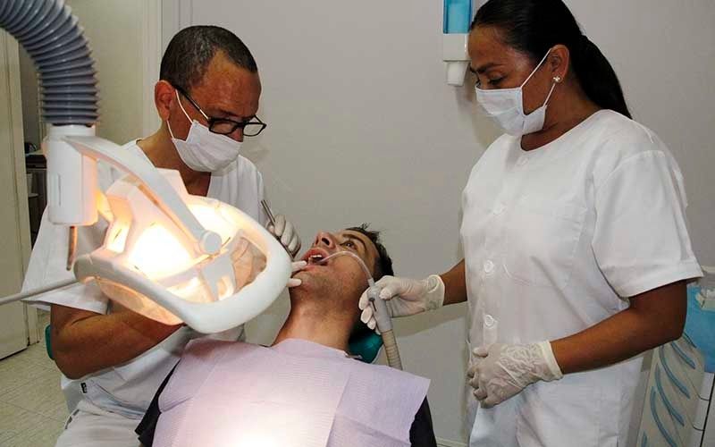 Un hombre está siendo examinado por dos dentistas.