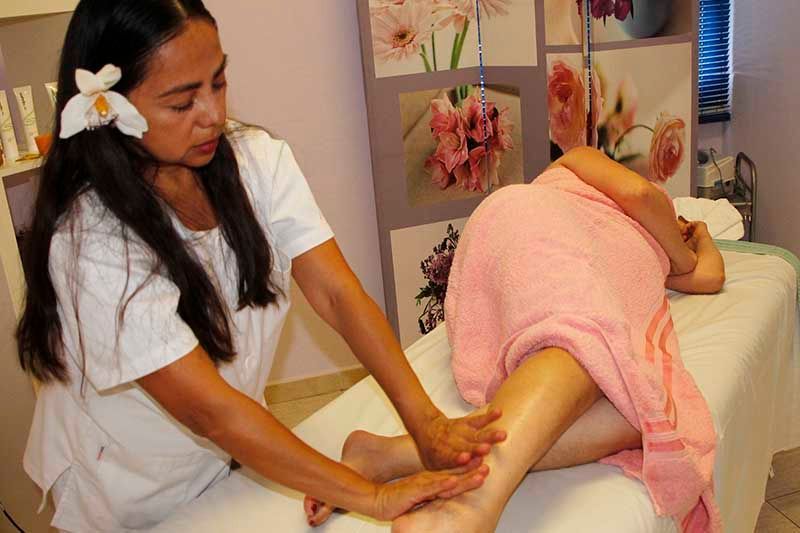 Una mujer está dando un masaje a una mujer envuelta en una toalla rosa.