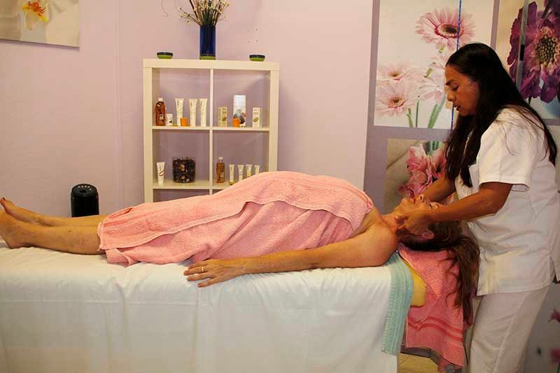 Una mujer está recibiendo un masaje en un spa mientras está envuelta en una toalla rosa.