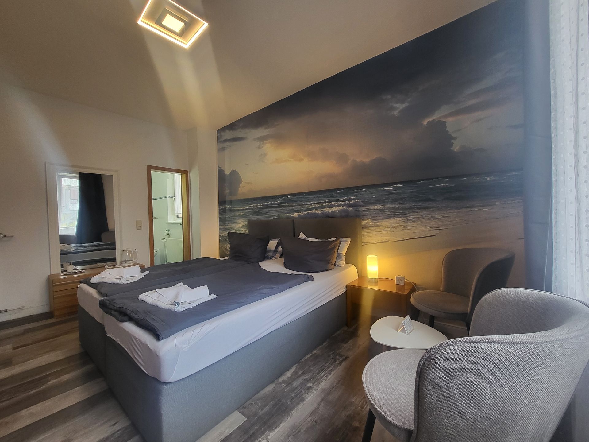 Ein Hotelzimmer mit einem Bett, Stühlen und einem Gemälde an der Wand.