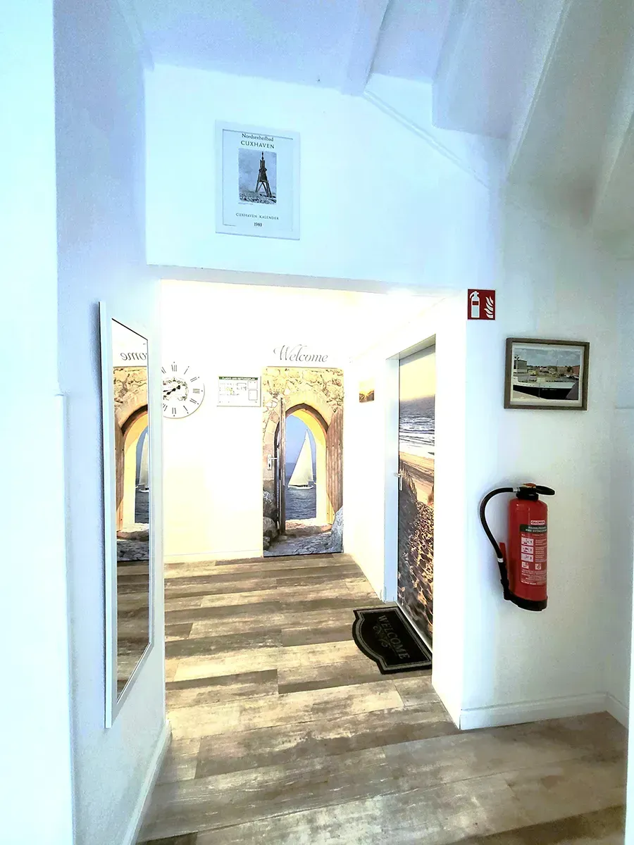 Ein Flur mit einem Feuerlöscher an der Wand und einem Spiegel an der Wand.