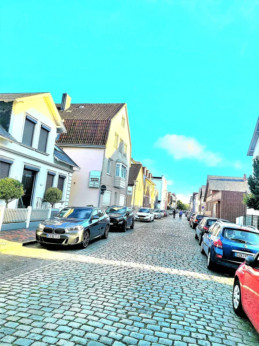 Auf einer Kopfsteinpflasterstraße parken eine Reihe Autos.