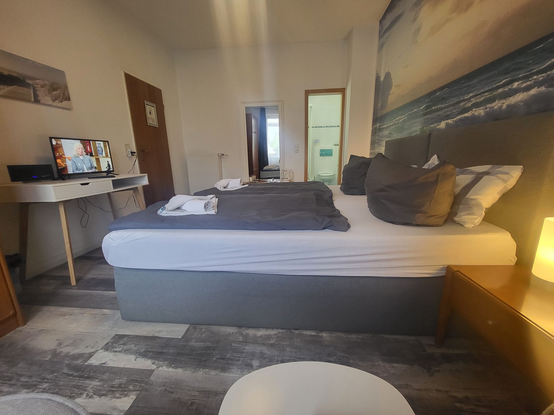 Ein Schlafzimmer mit großem Bett, Schreibtisch und Fernseher.