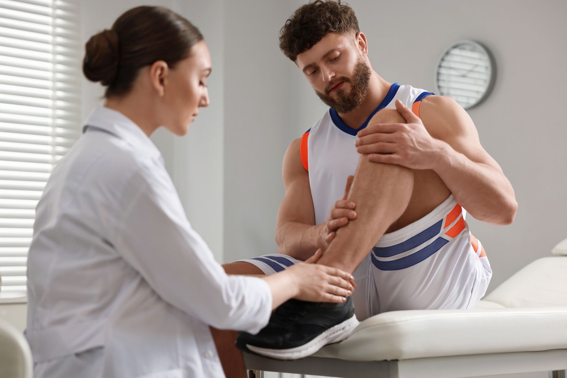 Un profesional sanitario examina la pierna de un jugador de baloncesto en una clínica.