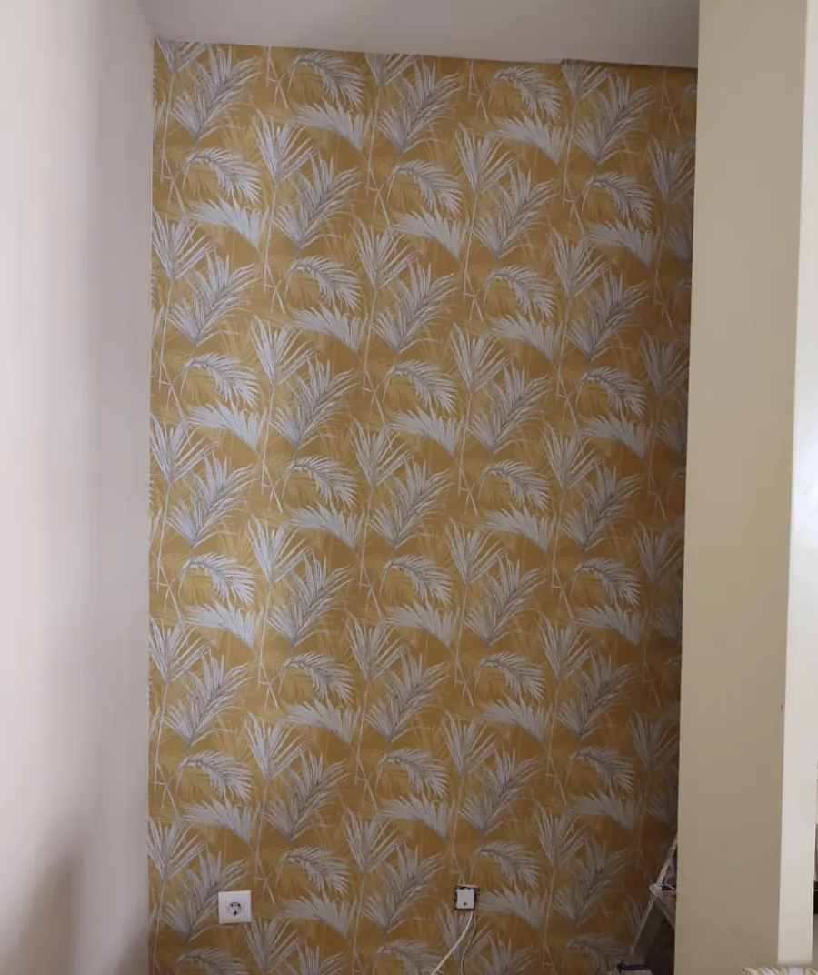Pequeño hueco con papel pintado floral amarillo y paredes laterales blancas sin revestimiento.