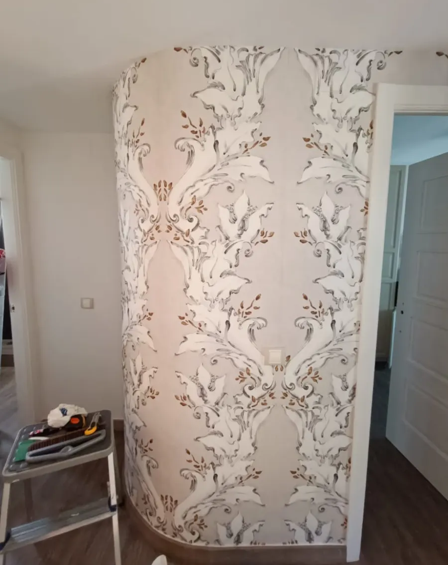Pasillo con papel pintado floral beige, molduras blancas y una pequeña mesa auxiliar a la izquierda.