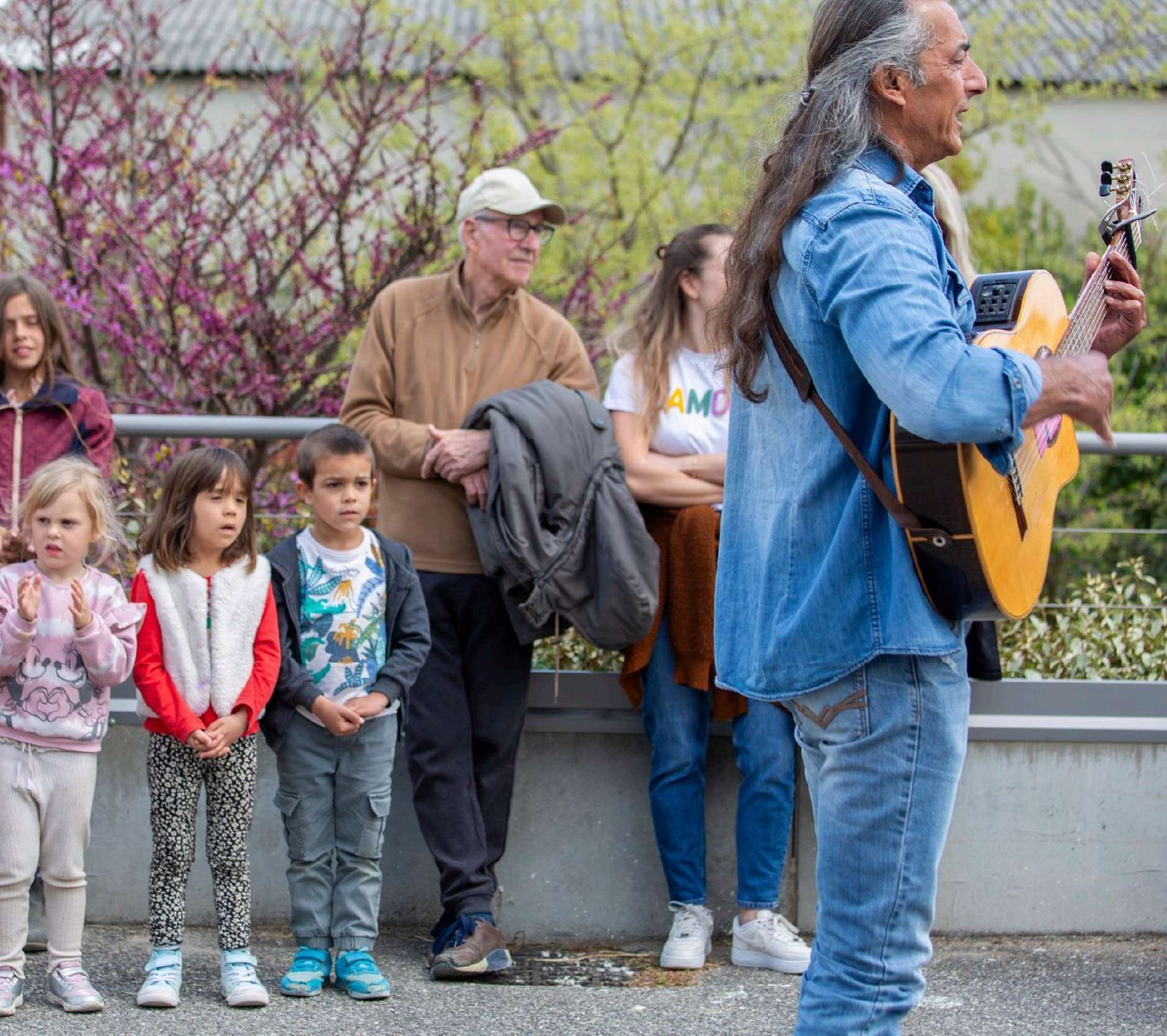 Des enfants et des adultes qui écoutent un guitariste