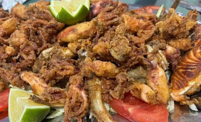 Plato de carne frita con rodajas de lima y tomate.