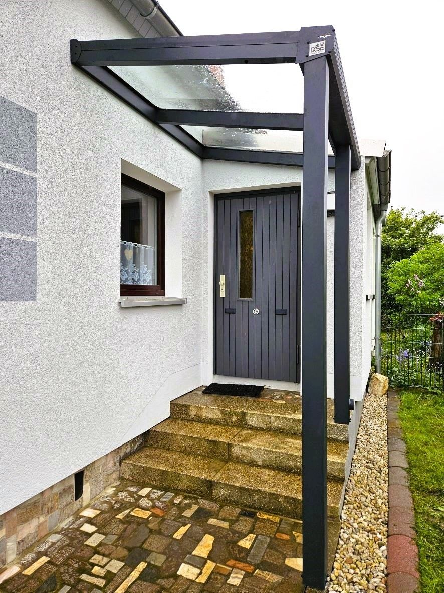 Die Vordertür eines Hauses mit einem Glasdach darüber.