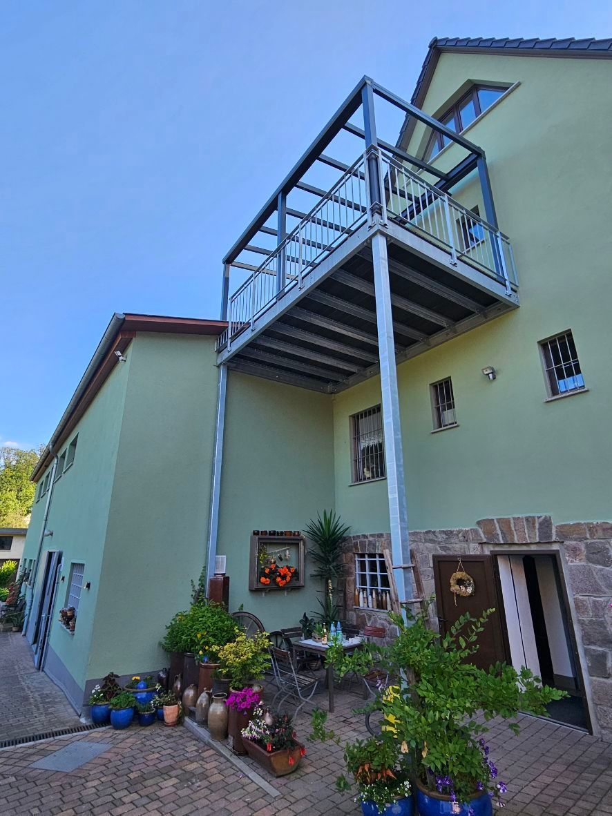 Ein Gewächshaus mit einem Balkon an der Seite.