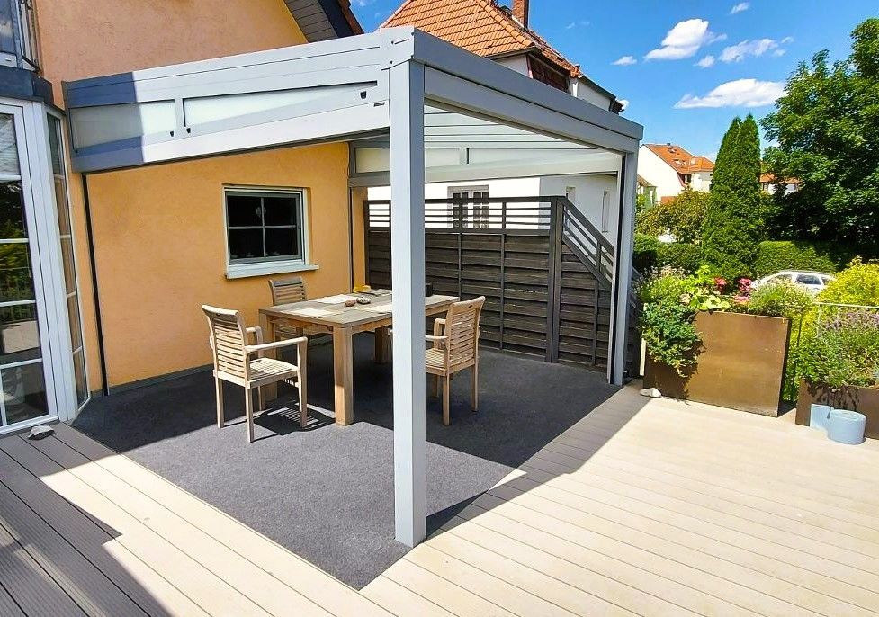 Eine Terrasse mit Tisch und Stühlen unter einer Pergola
