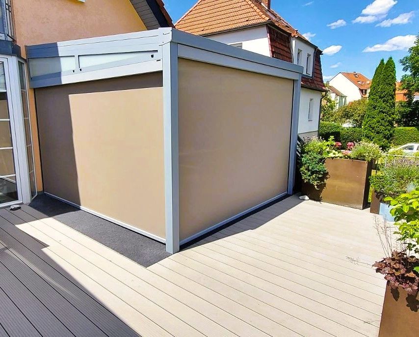 Eine Terrasse mit Pergola und einem Haus im Hintergrund.