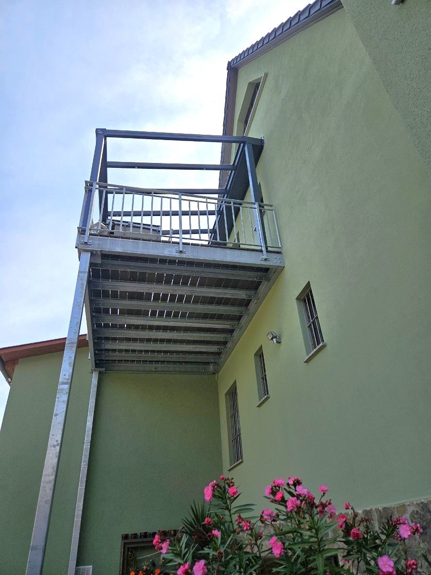 Ein grünes Gebäude mit einem Balkon an der Seite