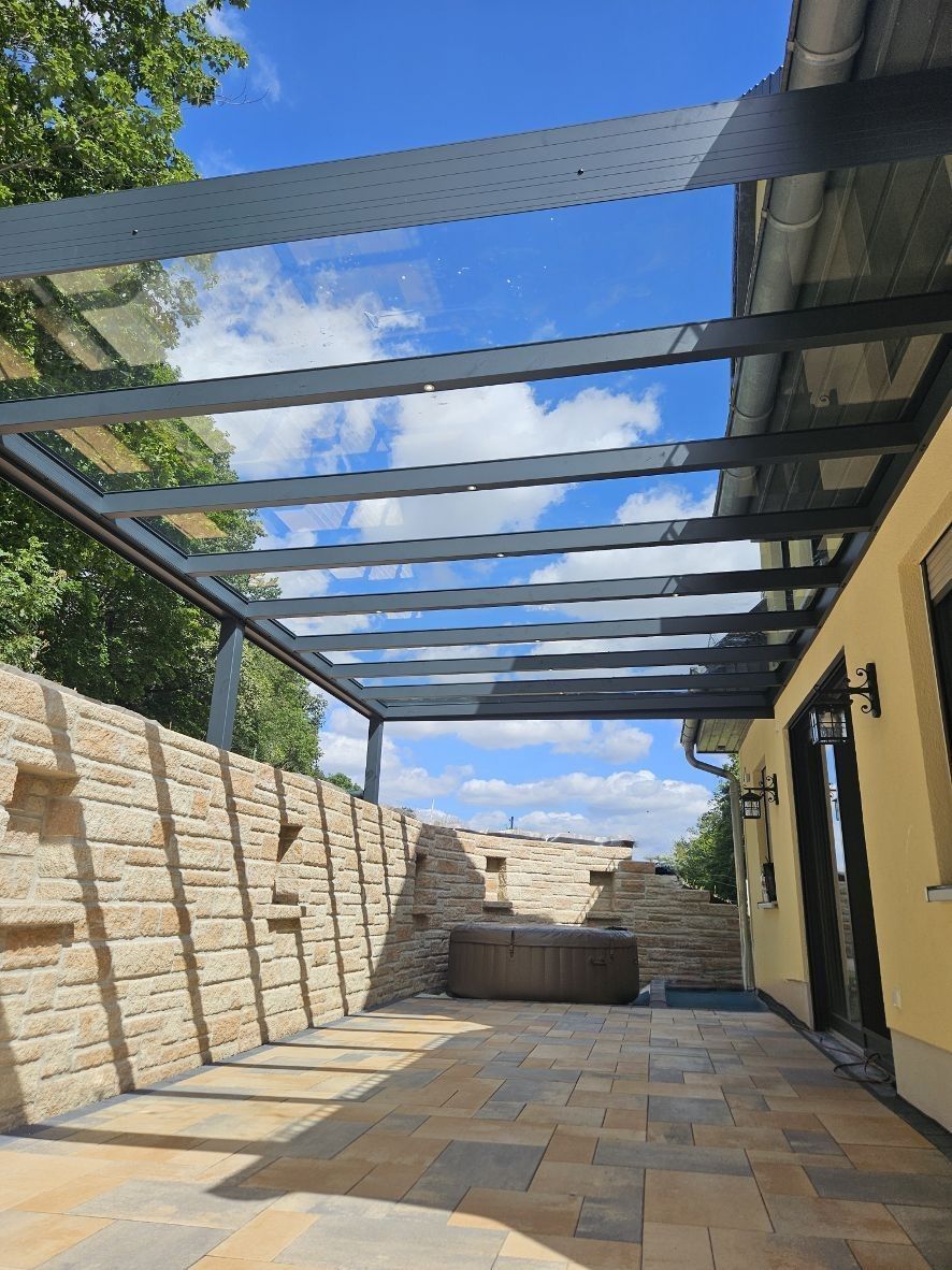 Eine Terrasse mit Glasdach und Steinmauer