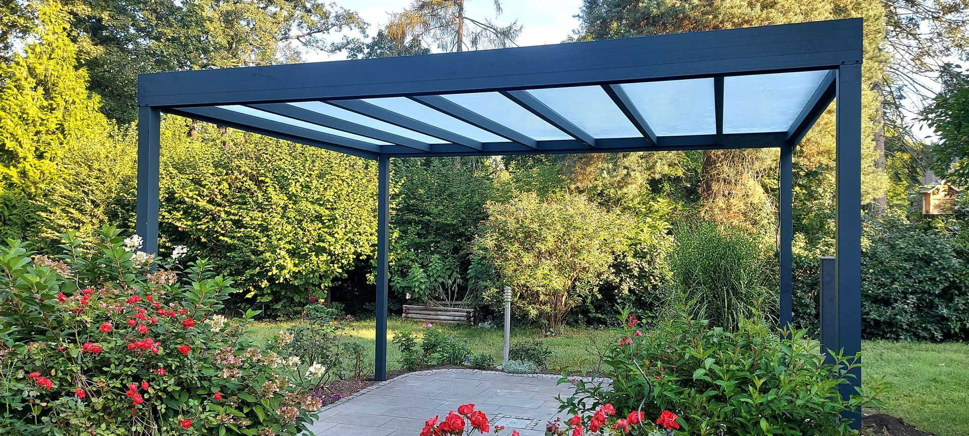 Eine Pergola steht inmitten eines von Bäumen umgebenen Gartens.