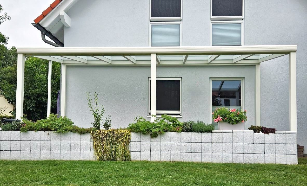 Ein weißes Haus mit einer weißen Pergola an der Seite