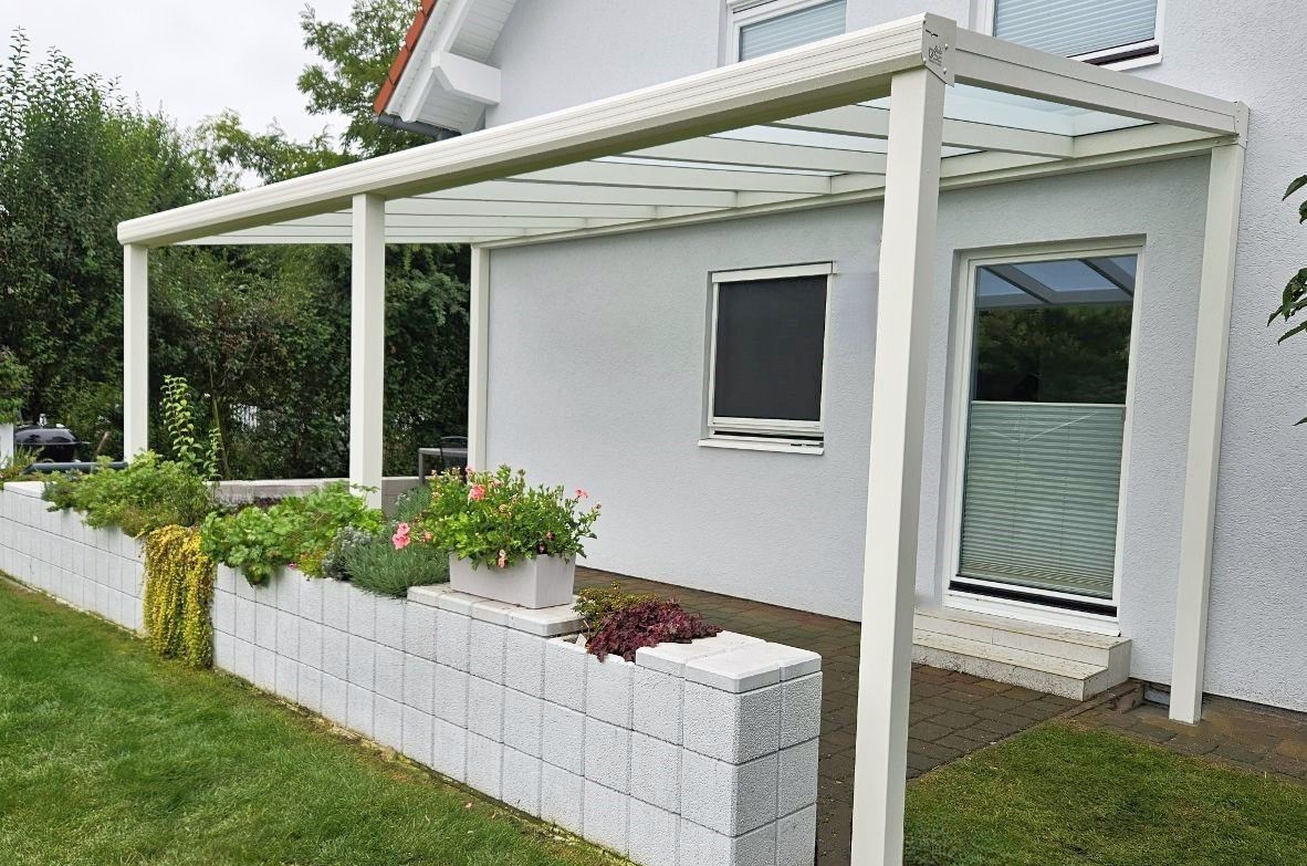 Ein weißes Haus mit einer Glaspergola an der Seite.