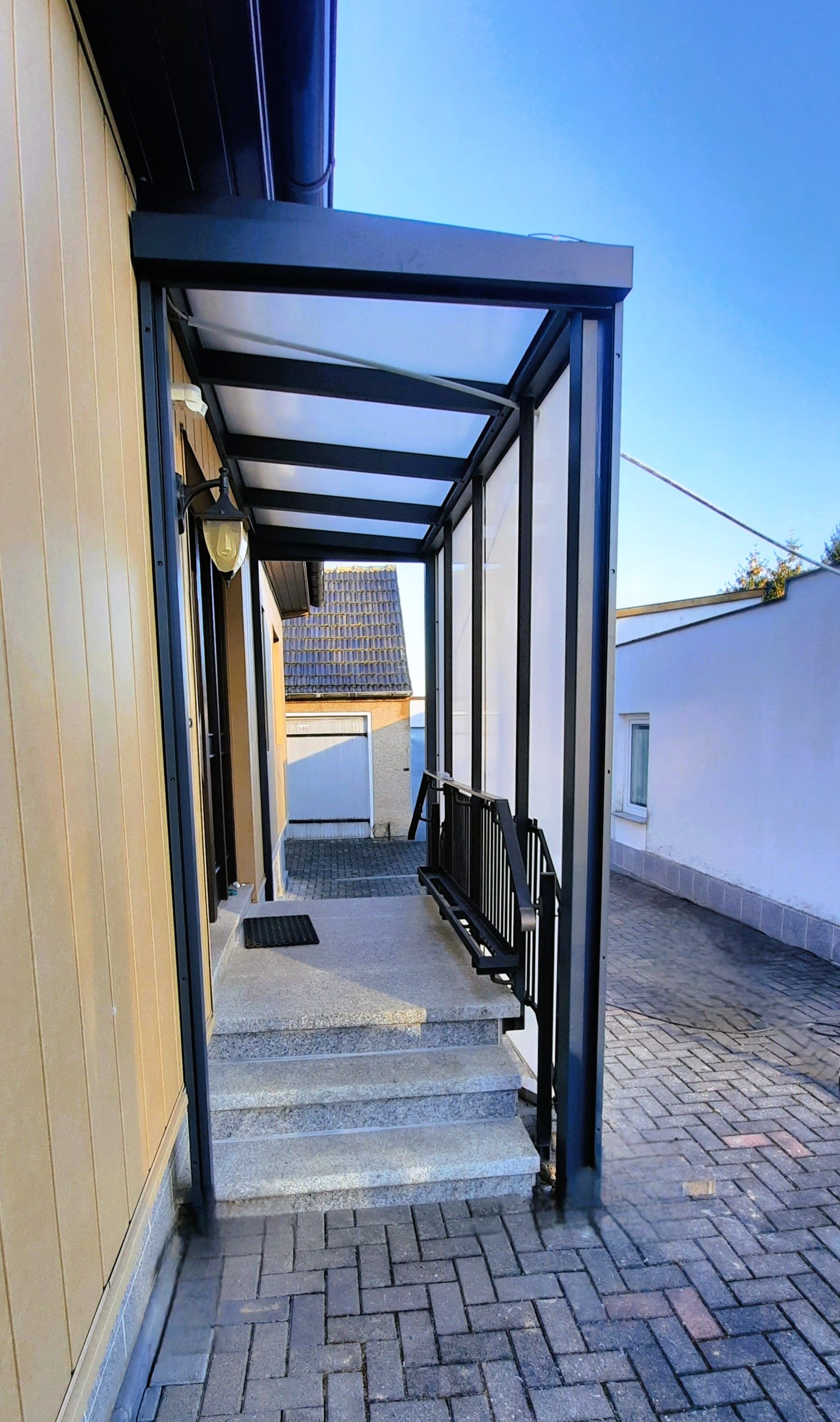 Ein Ziegelweg, der zu einem Haus mit einem Vordach führt.