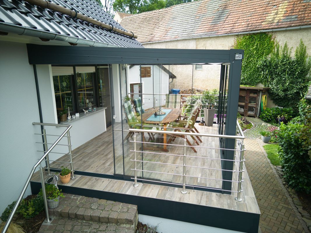 Eine Terrasse mit einem Tisch und Stühlen vor einem Haus.