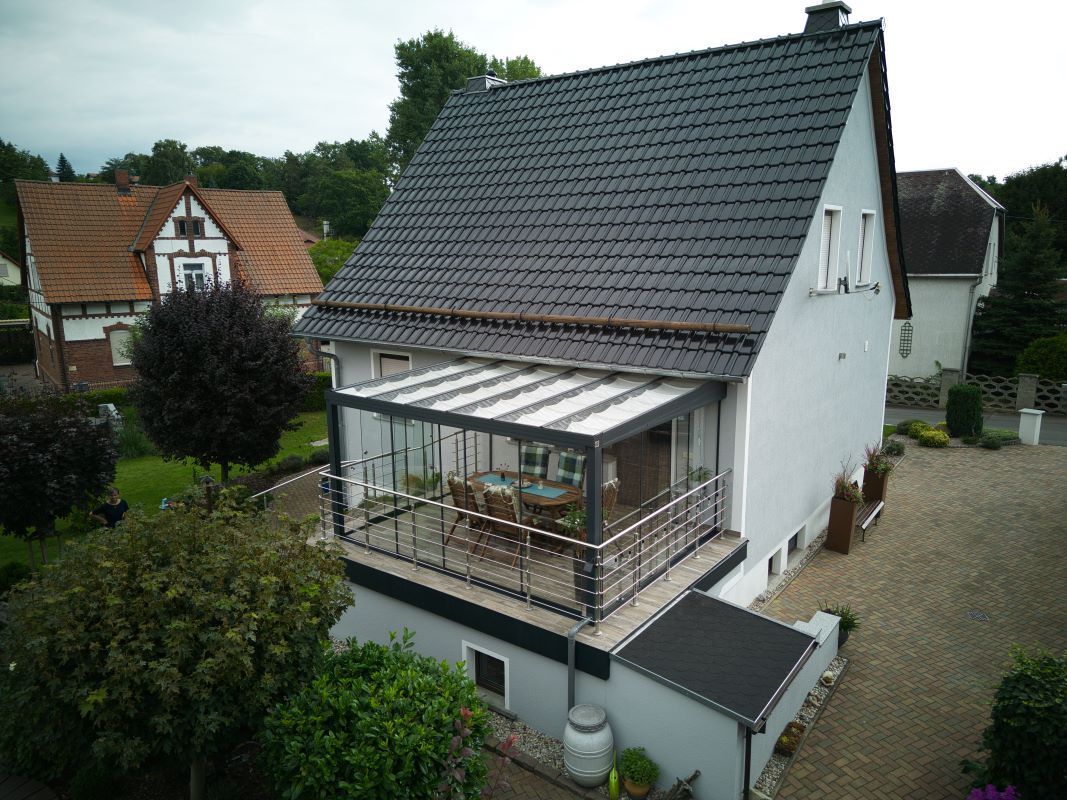 Eine Luftaufnahme eines weißen Hauses mit einem schwarzen Dach und einem Balkon.