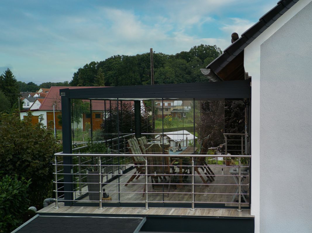 Es gibt einen Balkon mit einem Tisch und Stühlen.