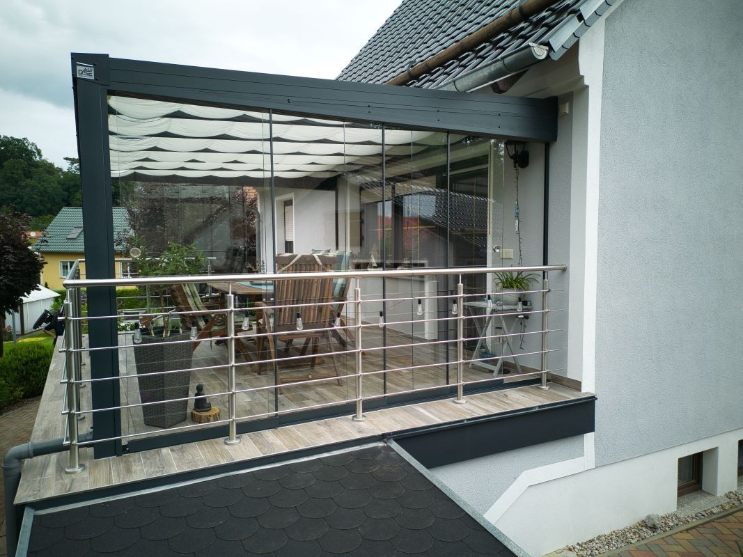 Ein Balkon mit Glasschiebetür und Edelstahlgeländer.