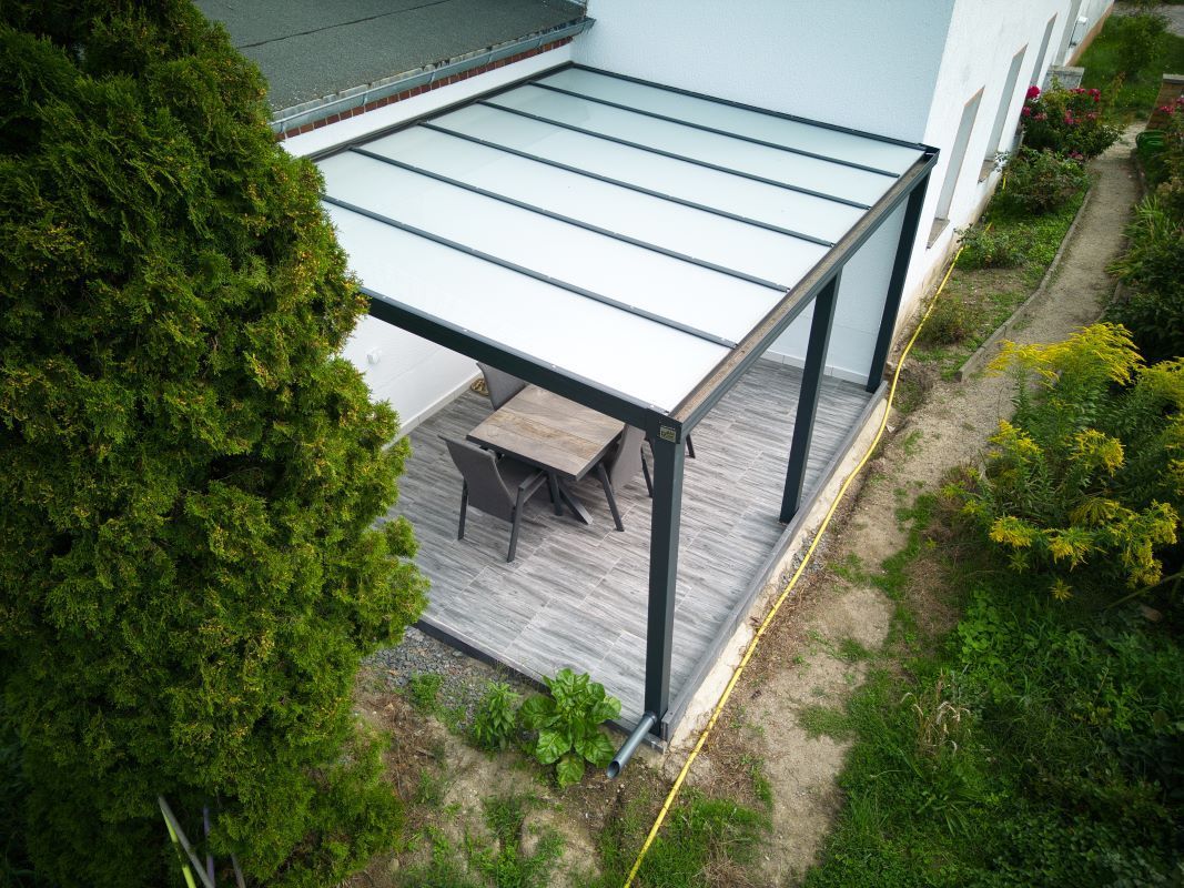 Eine Luftaufnahme einer Terrasse mit einem Tisch und Stühlen unter einer Pergola.