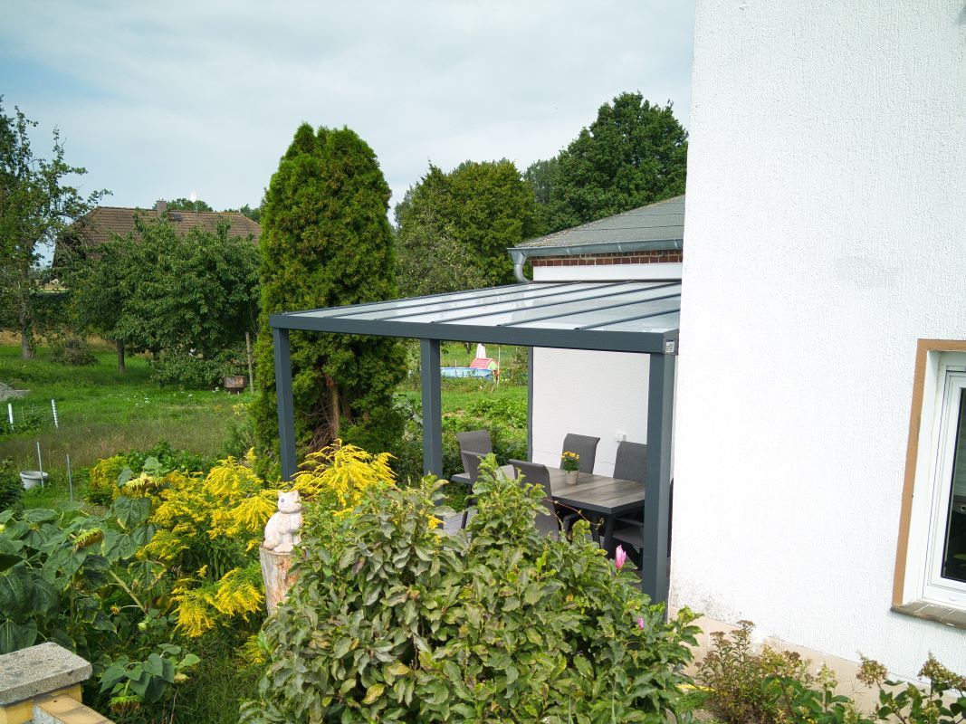 Ein weißes Haus mit einer Pergola und einem Tisch und Stühlen im Hinterhof.